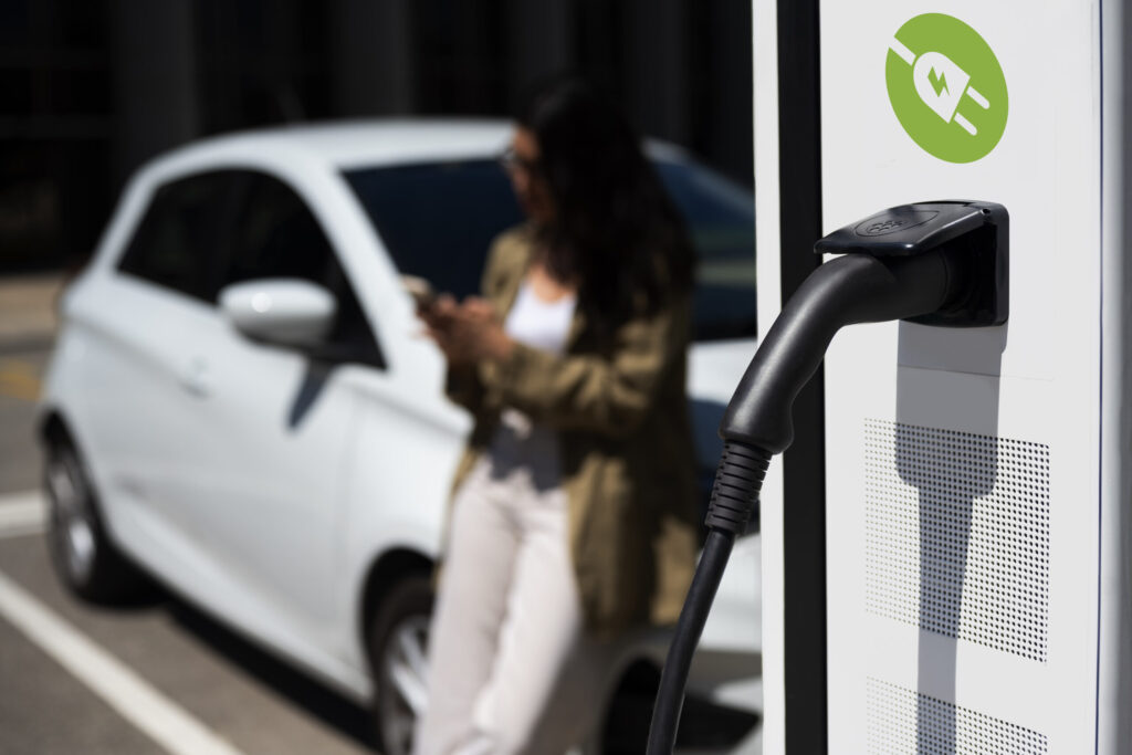 nabíjanie elektromobilu, v pozadí žena