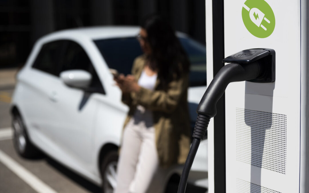 nabíjanie elektromobilu, v pozadí žena